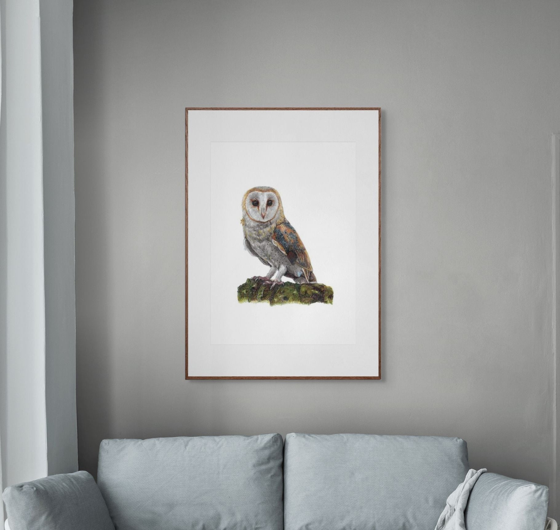 Framed artwork of an owl on a gray wall above a light blue sofa.