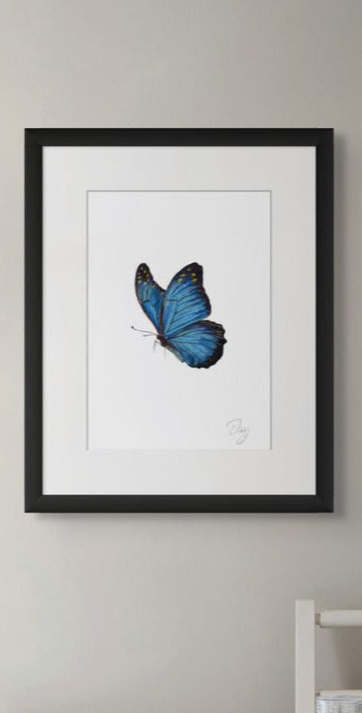 Framed artwork of a blue butterfly on a neutral wall.