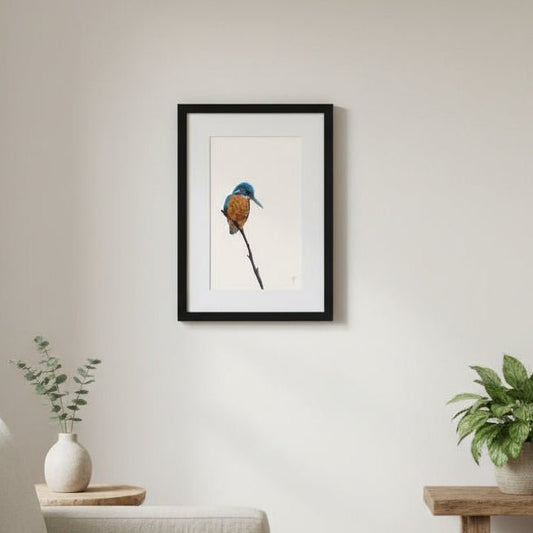 Framed artwork of a bird on a wall in a living room with a couch and plants.